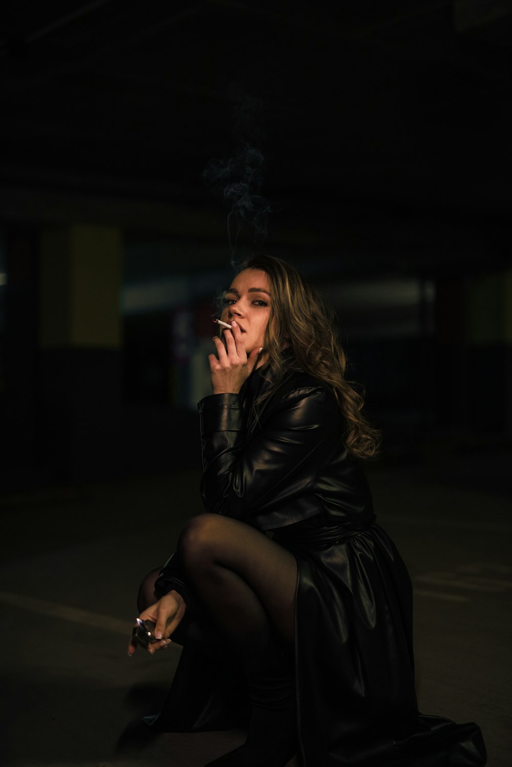 a woman in a black dress smoking a cigarette