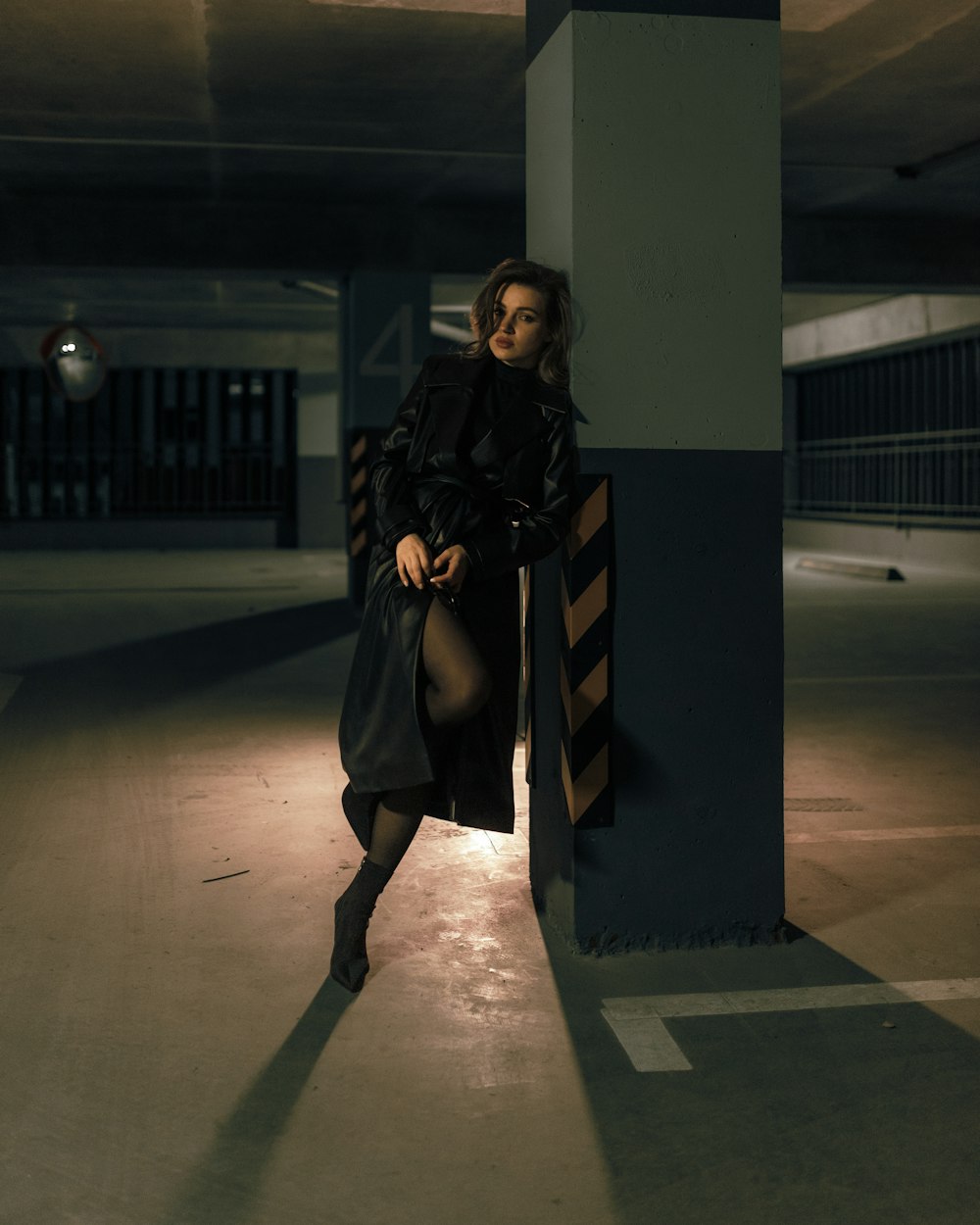 a woman leaning against a pillar in a parking garage