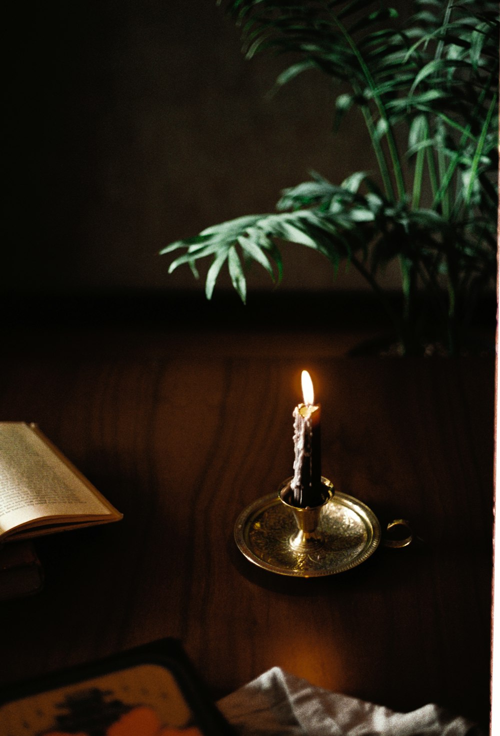 a lit candle sitting on top of a table next to a book