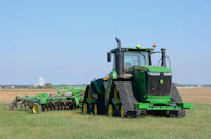 A modern tractor with implements attached, parked on a farm.