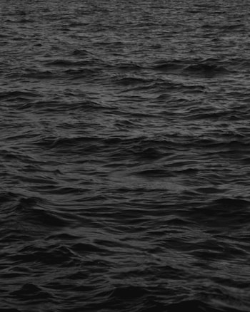 Dark ocean waves in a monochromatic color palette, creating a sense of calm yet mysterious atmosphere.