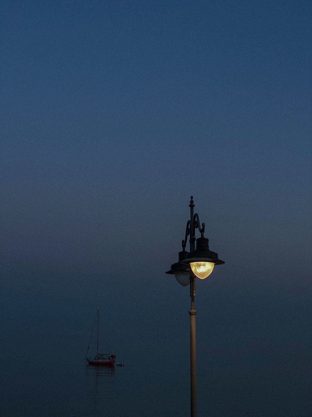 a street light with a boat in the background