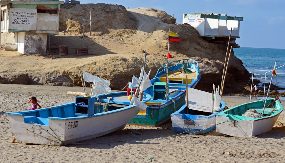 a couple of boats sitting on top of a sandy beach