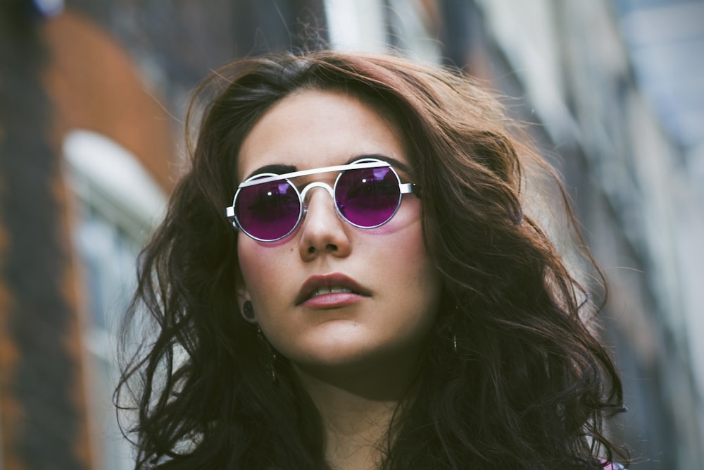 a woman wearing sunglasses standing in front of a building