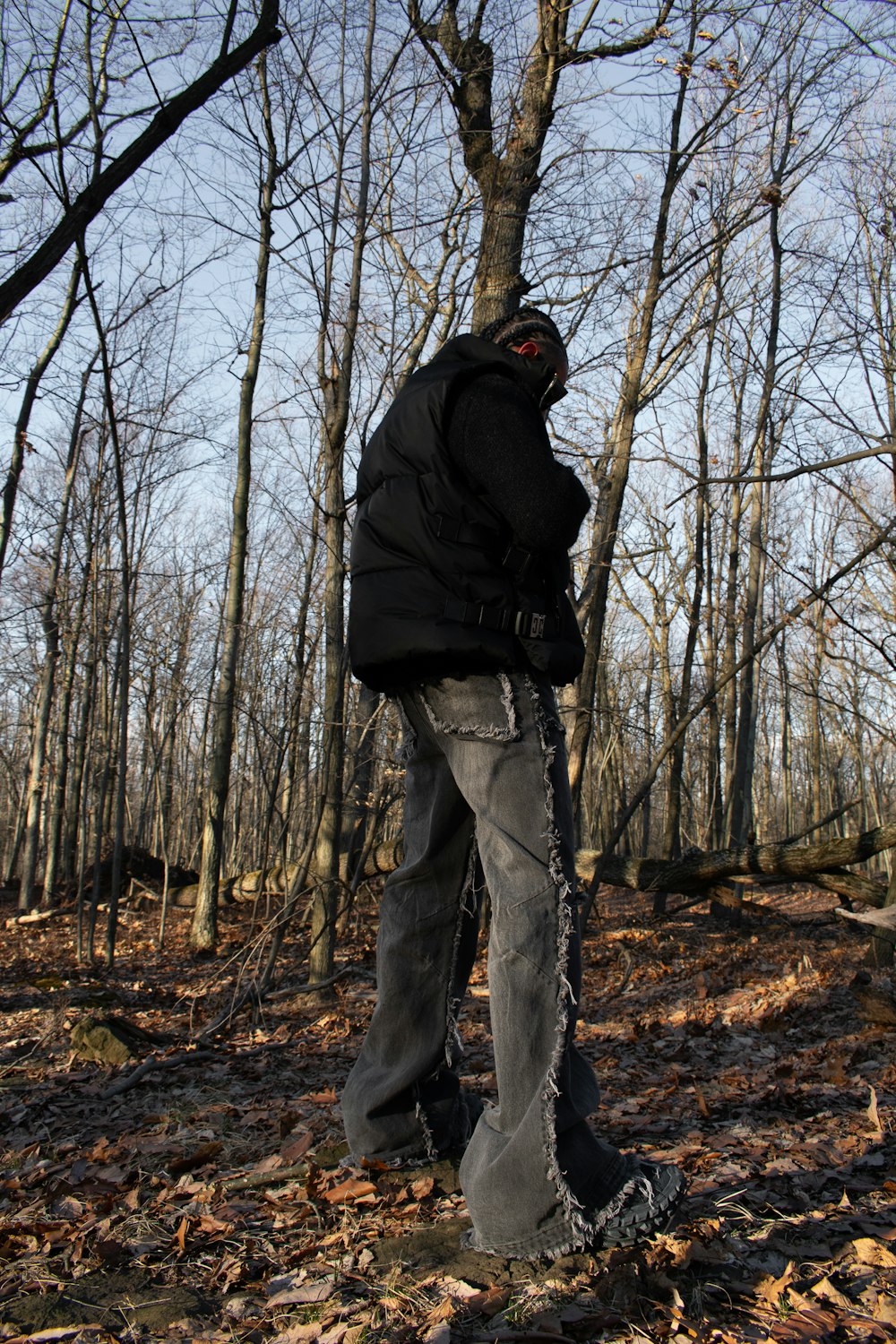 a man standing next to a tree in a forest