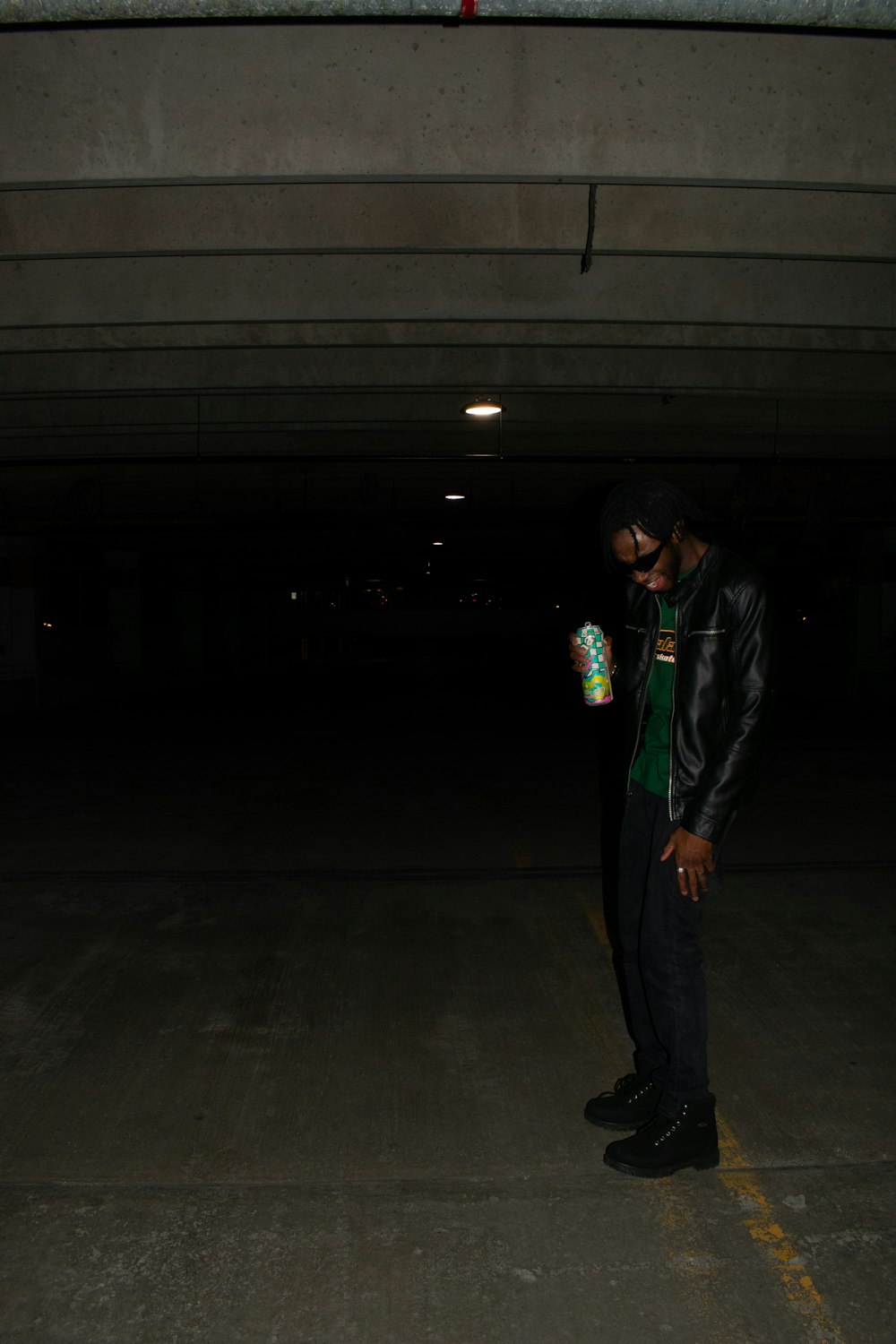 a man standing in a parking garage holding a bottle of water