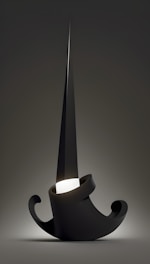 A sculptural, abstract lamp design with a sharp, pointed structure emanating from a coiled, minimalistic base. The primary material appears dark and glossy, with a subtle glow at the center creating a dramatic effect against the muted background.