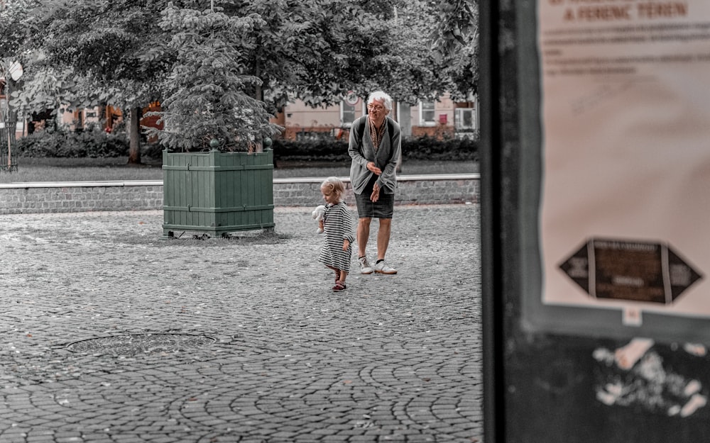 a man and a little girl walking down a cobblestone street