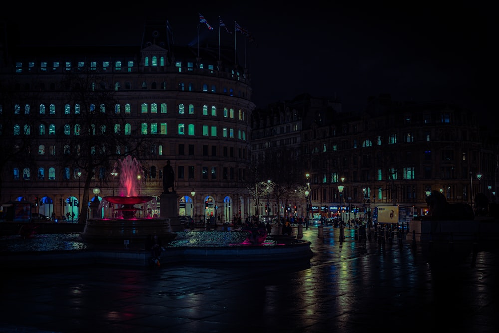 a city at night with a fountain lit up