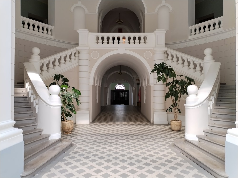 a large white building with a staircase and potted plants