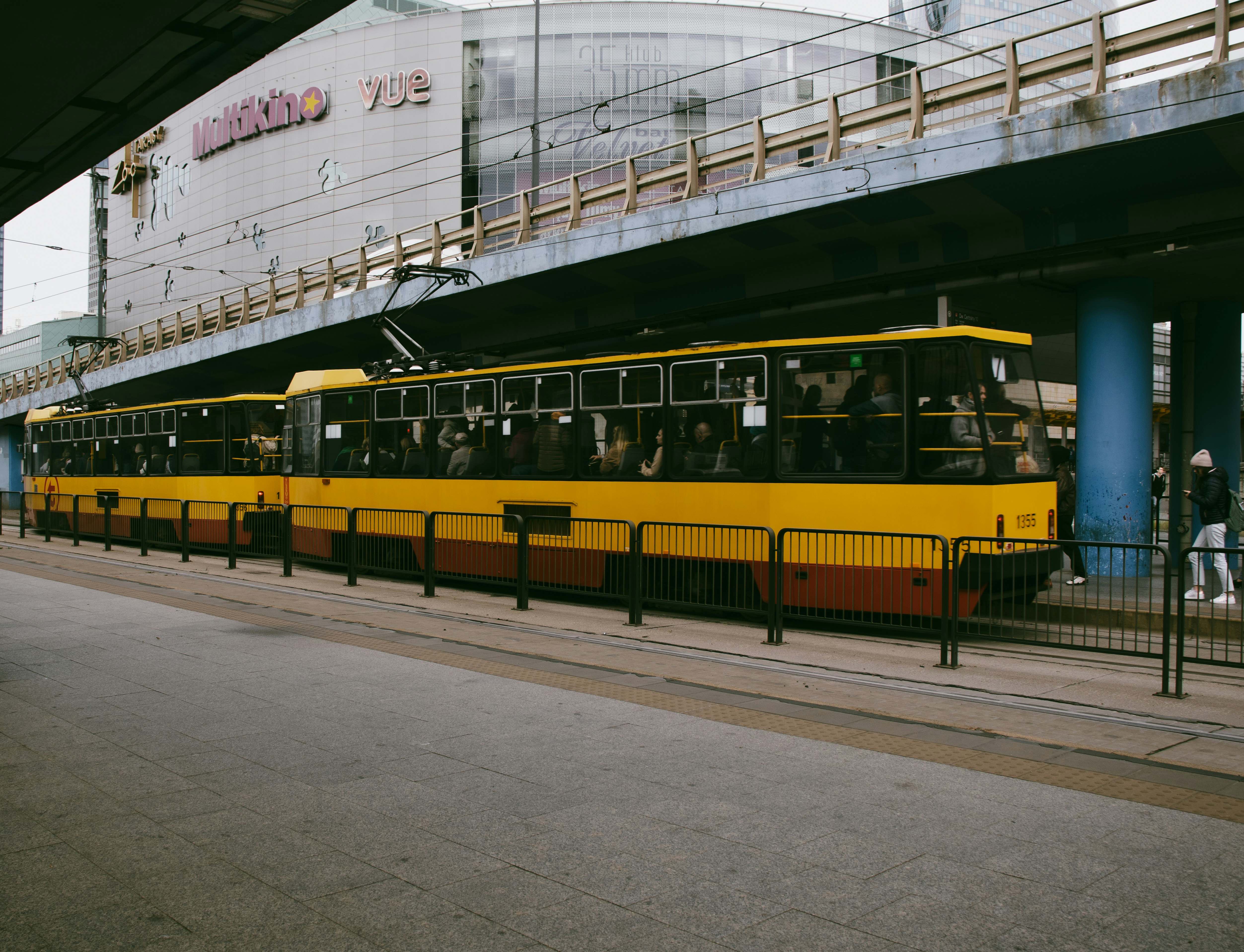 a yellow and red train traveling under a bridge