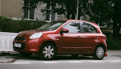 Compact red car parked near a downtown café on a bright day.