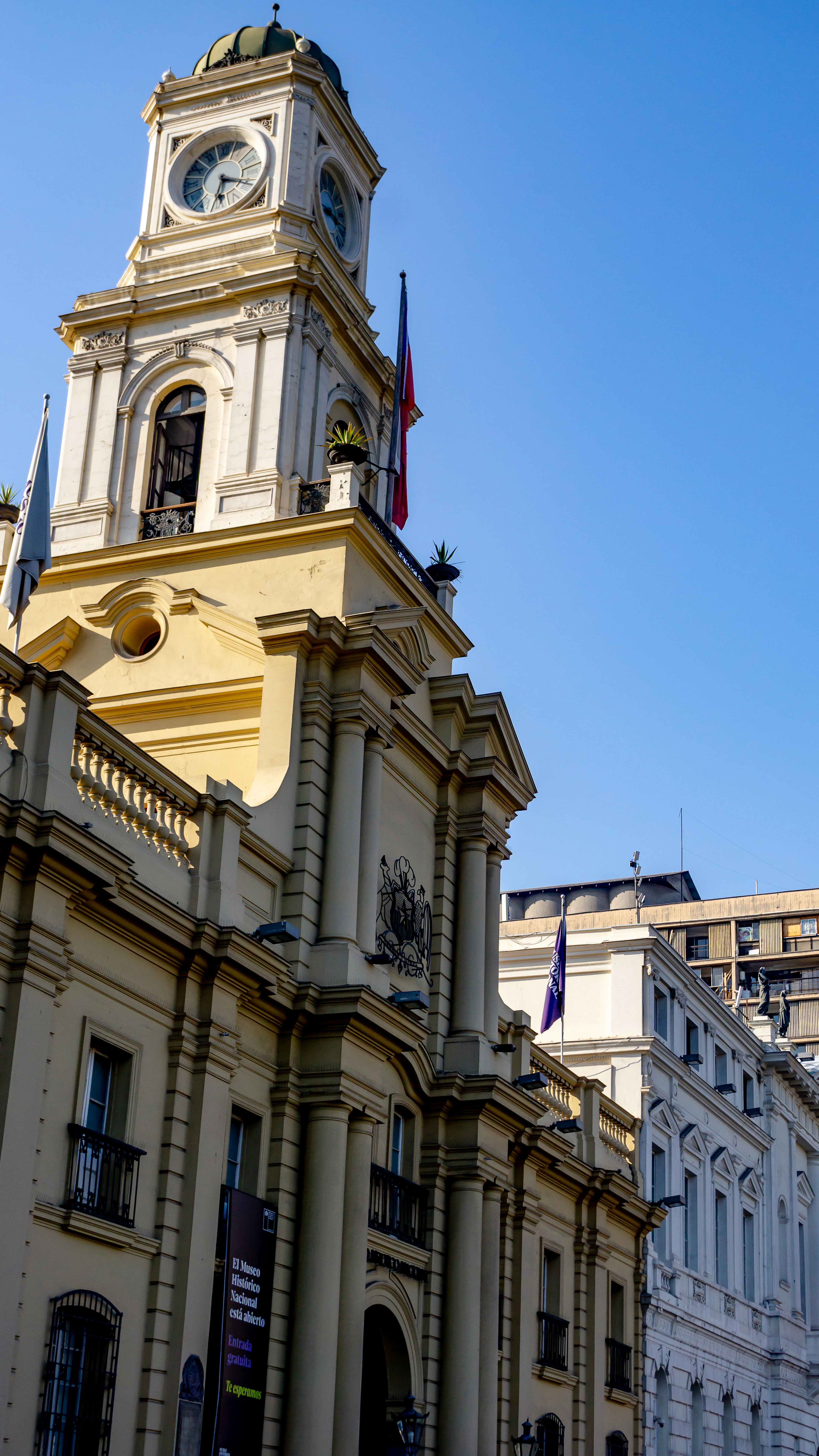 The clock tower and colonnade on Santiago's Plaza de Armas, flags flying from the balcony