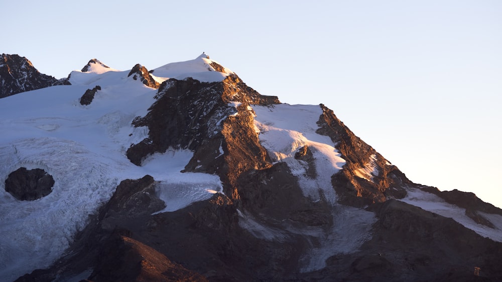 a large mountain covered in snow with a sky background