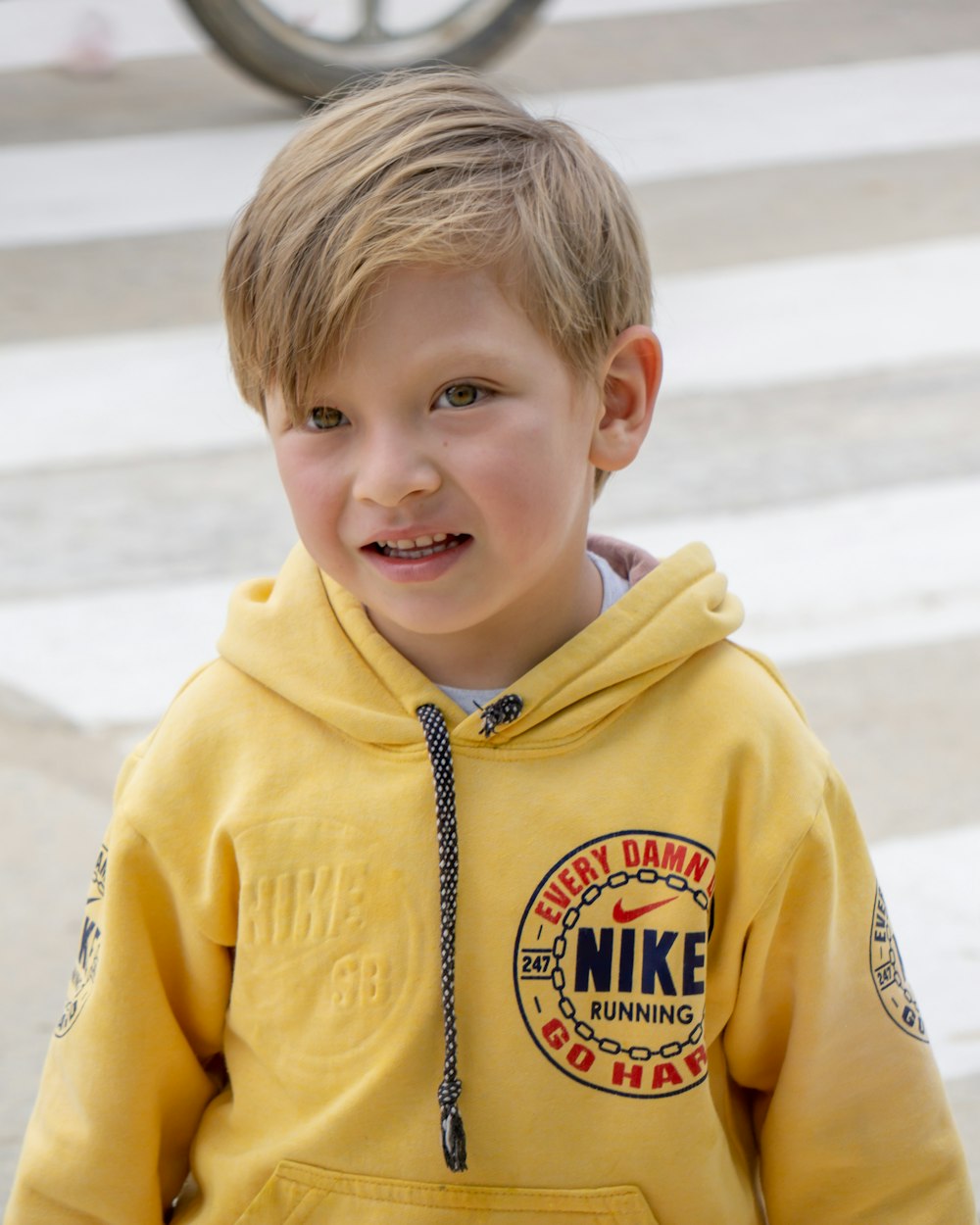 Um garoto de capuz amarelo sorri para a câmera