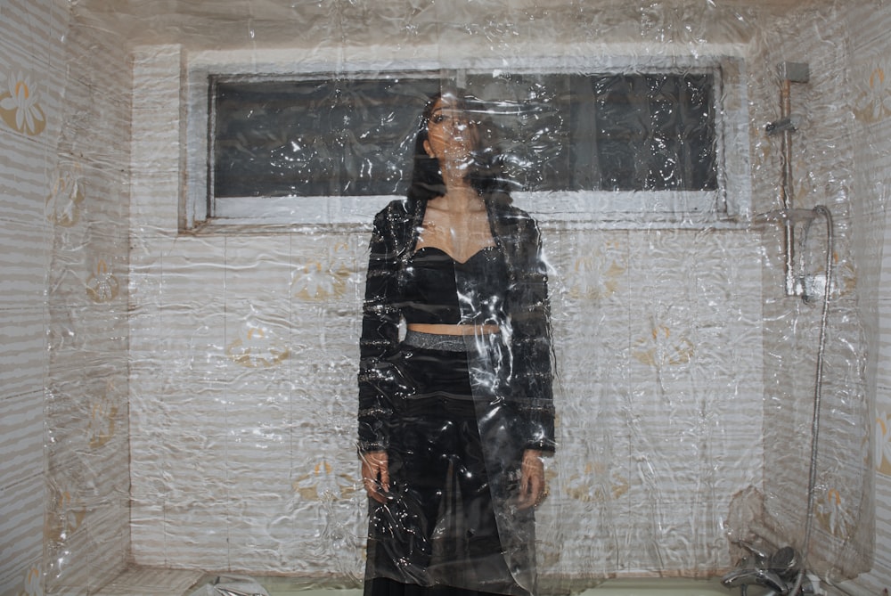 a woman standing in front of a window covered in plastic