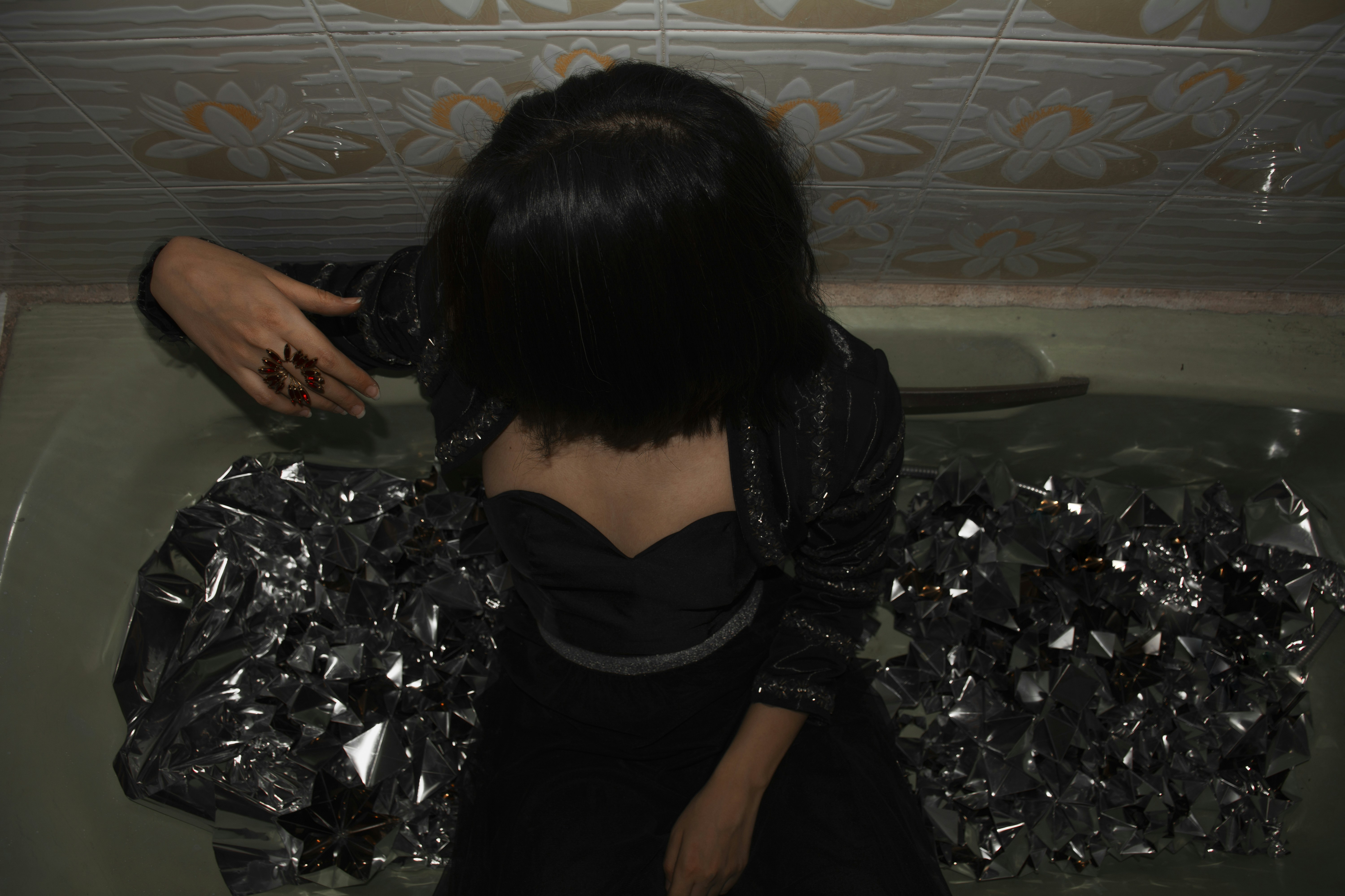 eine Frau, die mit einem Messer in der Hand in einer Badewanne sitzt