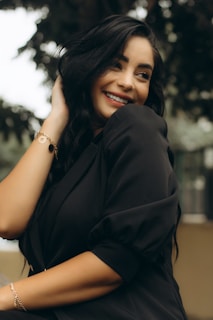 Smiling woman with long, glossy black hair extensions wearing a casual outfit.