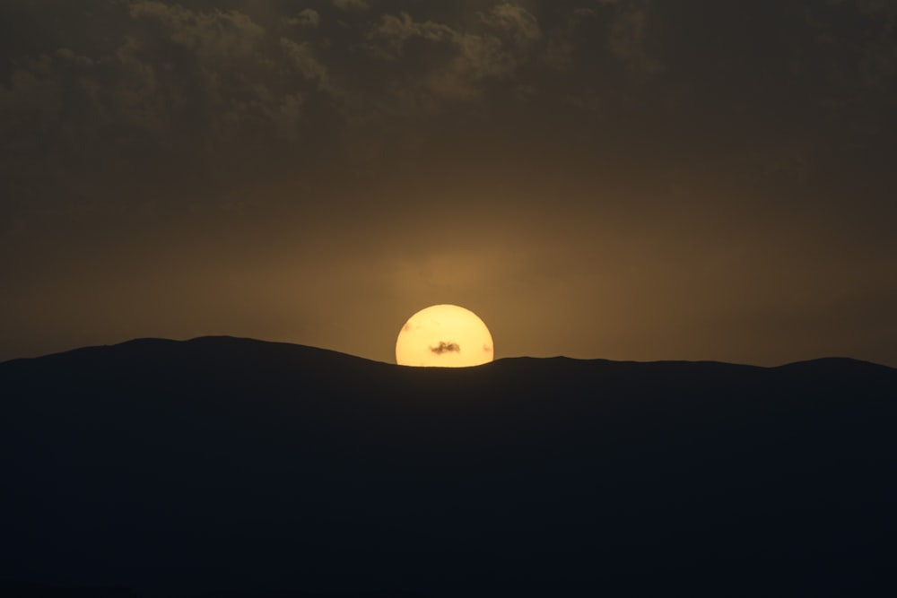 the sun is setting over a mountain range