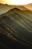 A panoramic view of rolling hills bathed in golden sunset light.