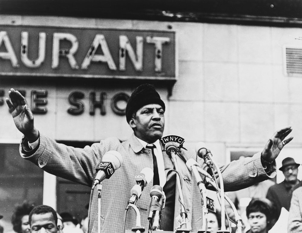 Bayard Rustin, half-length portrait, facing front, microphones in foreground.