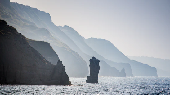 A serene photograph of Ireland’s rugged Atlantic coastline bathed in soft morning light, highlighting waves meeting rocky cliffs.