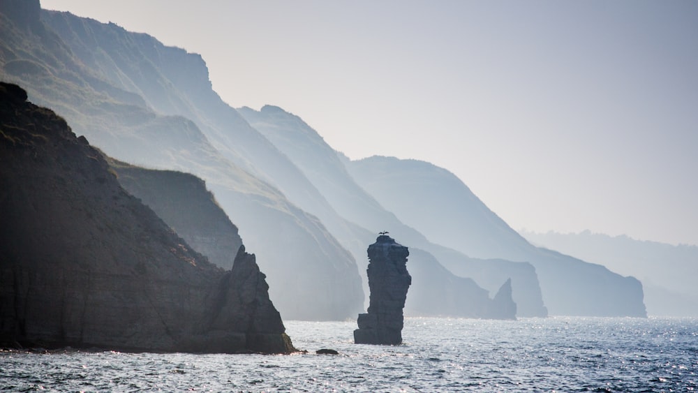 una persona in piedi su una roccia nel mezzo di uno specchio d'acqua