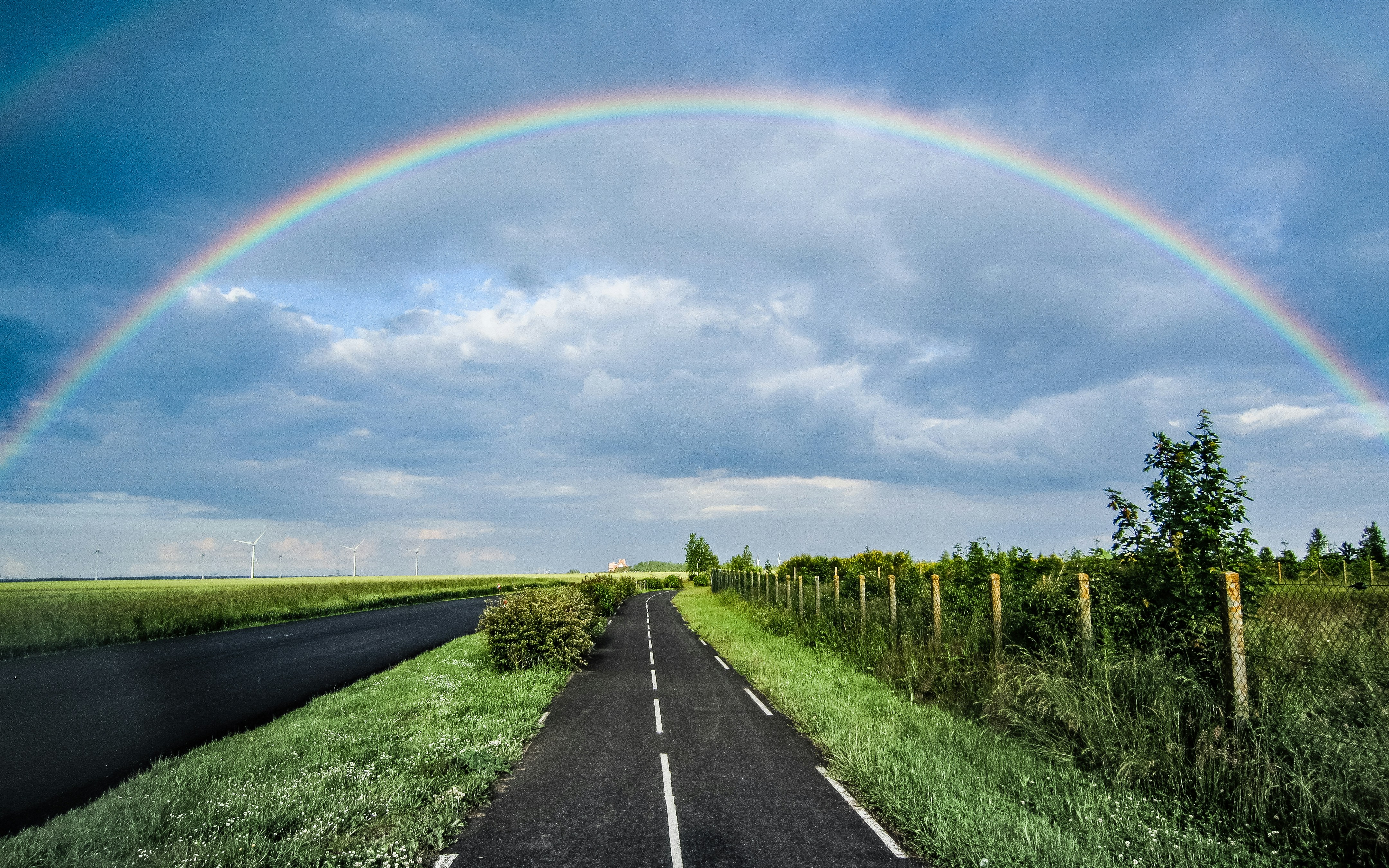 a double rainbow is seen over a rural road