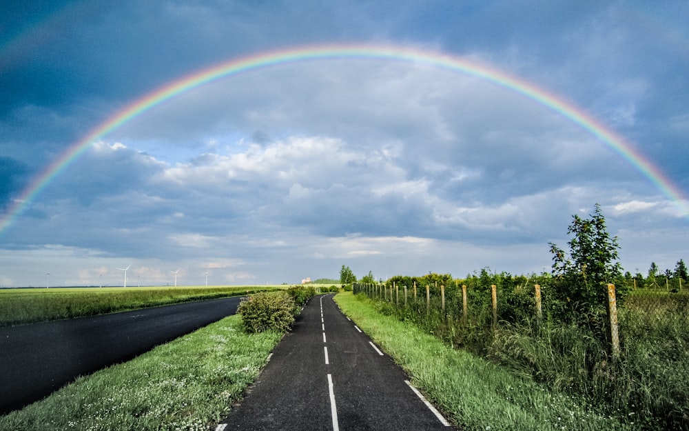a double rainbow is seen over a rural road