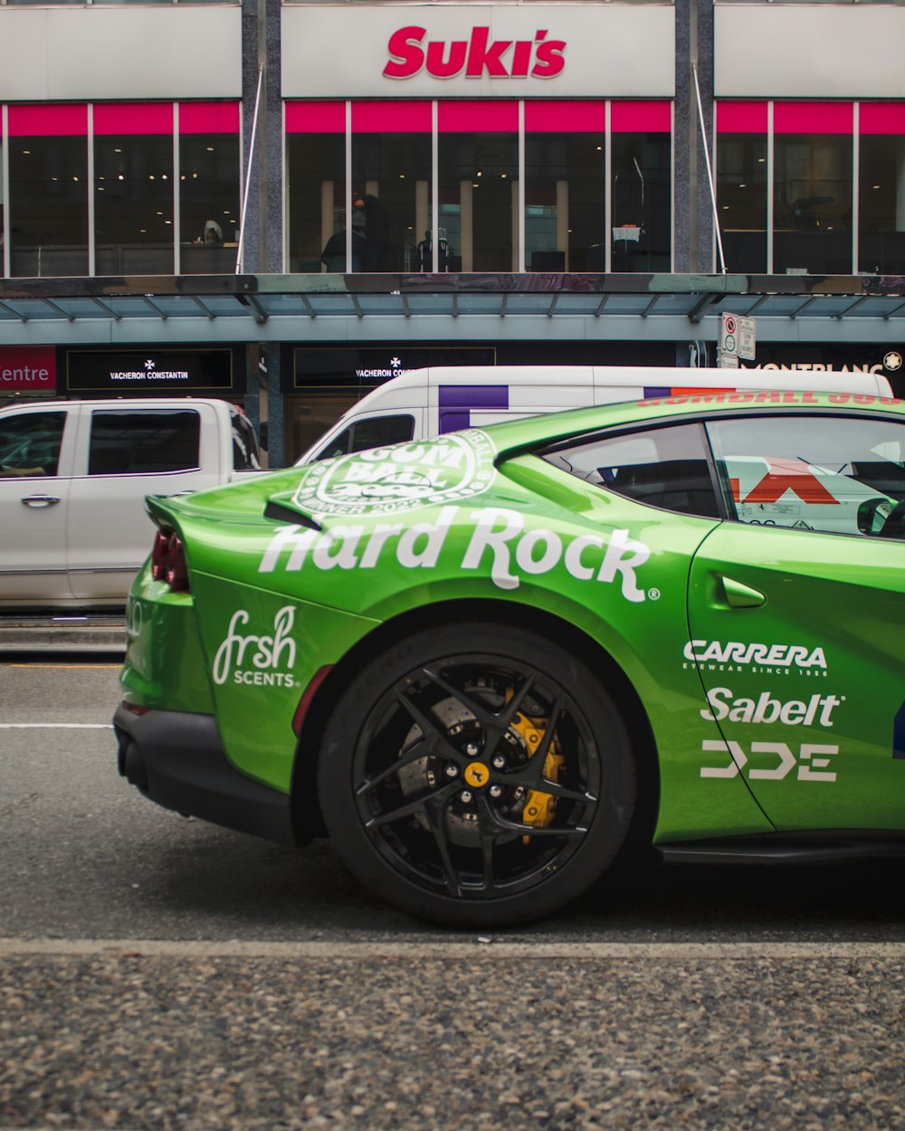 a green sports car parked in front of a store