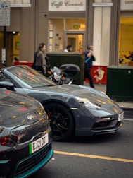 Two Mobi cars, one black and one gray, parked side by side on a city street.