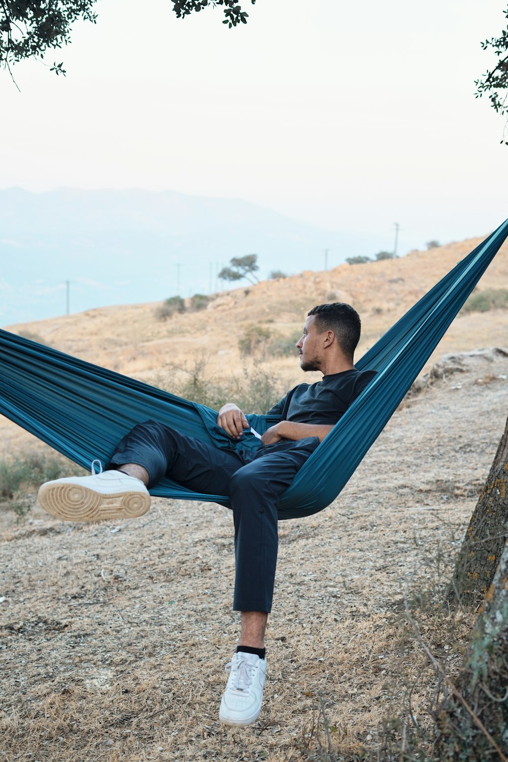 a man sitting in a hammock on a hill