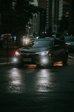 A sleek luxury car parked in front of a modern city skyline at dusk.