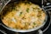 A large serving dish filled with fragrant biryani garnished with fresh cilantro. The dish showcases a colorful mix of rice, spices, and vegetables, with traces of white, yellow, and green hues throughout.
