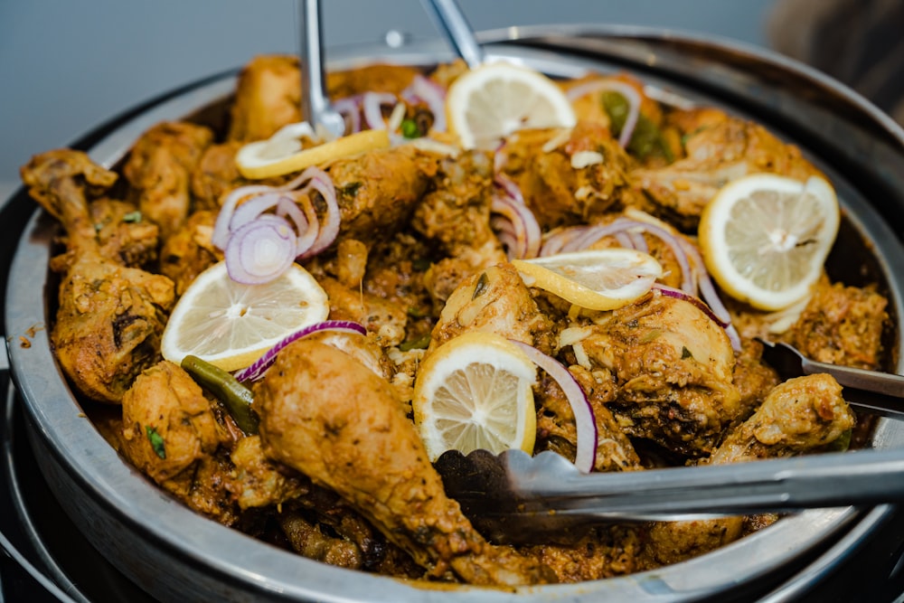 a plate of chicken with onions and lemons