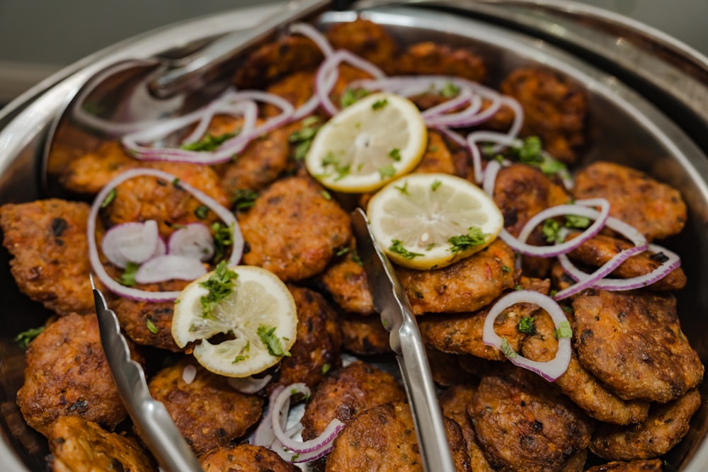 a metal bowl filled with chicken and onions