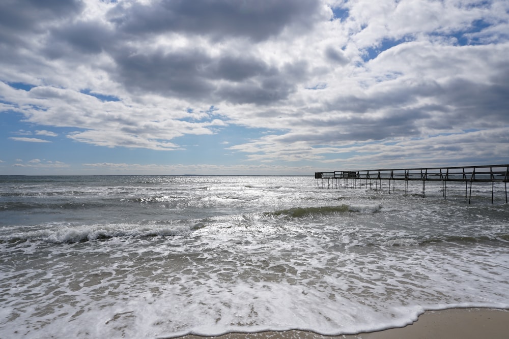 a pier on a beach with waves crashing in front of it