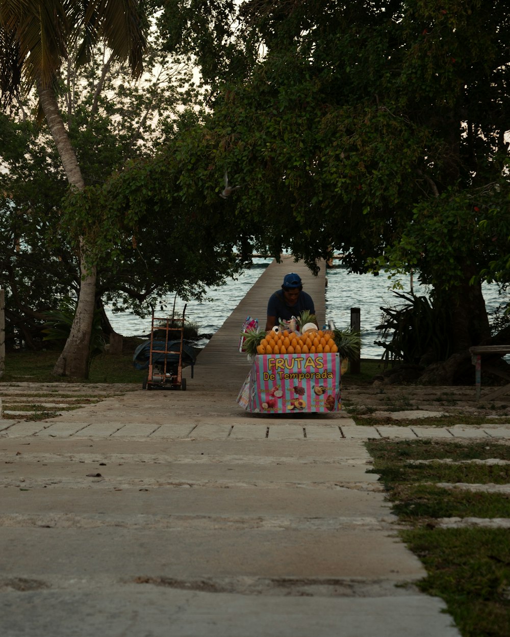 a man selling oranges on a sidewalk near the water