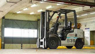 A modern electric forklift in action at a warehouse with dark blue and orange accents.