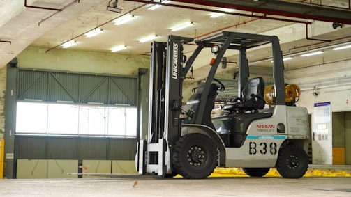 A group of trainees learning to operate a Manitou forklift in a bright workshop.
