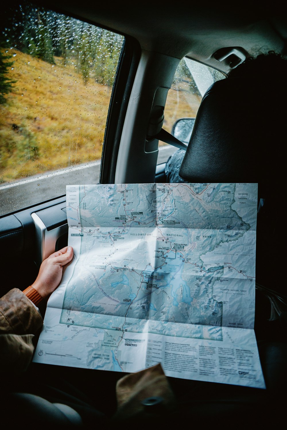 a person sitting in a car holding a map