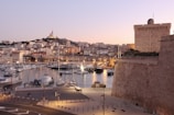 Sunset over Ceuta's fortified old town with boats docked in the harbor.