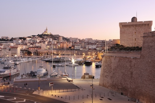 Sunset over Ceuta's fortified old town with boats docked in the harbor.