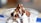 A creamy vanilla ice cream topped with a rich chocolate sauce and sprinkled with crushed nuts, served in a clear cup. The background is softly blurred, emphasizing the smooth texture and vibrant colors of the dessert.