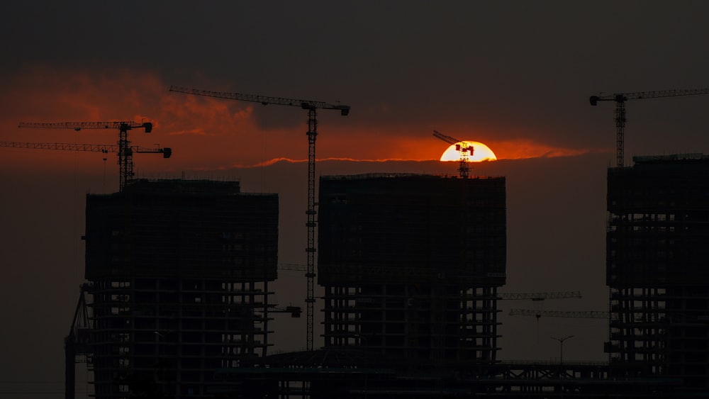 the sun is setting behind a building under construction