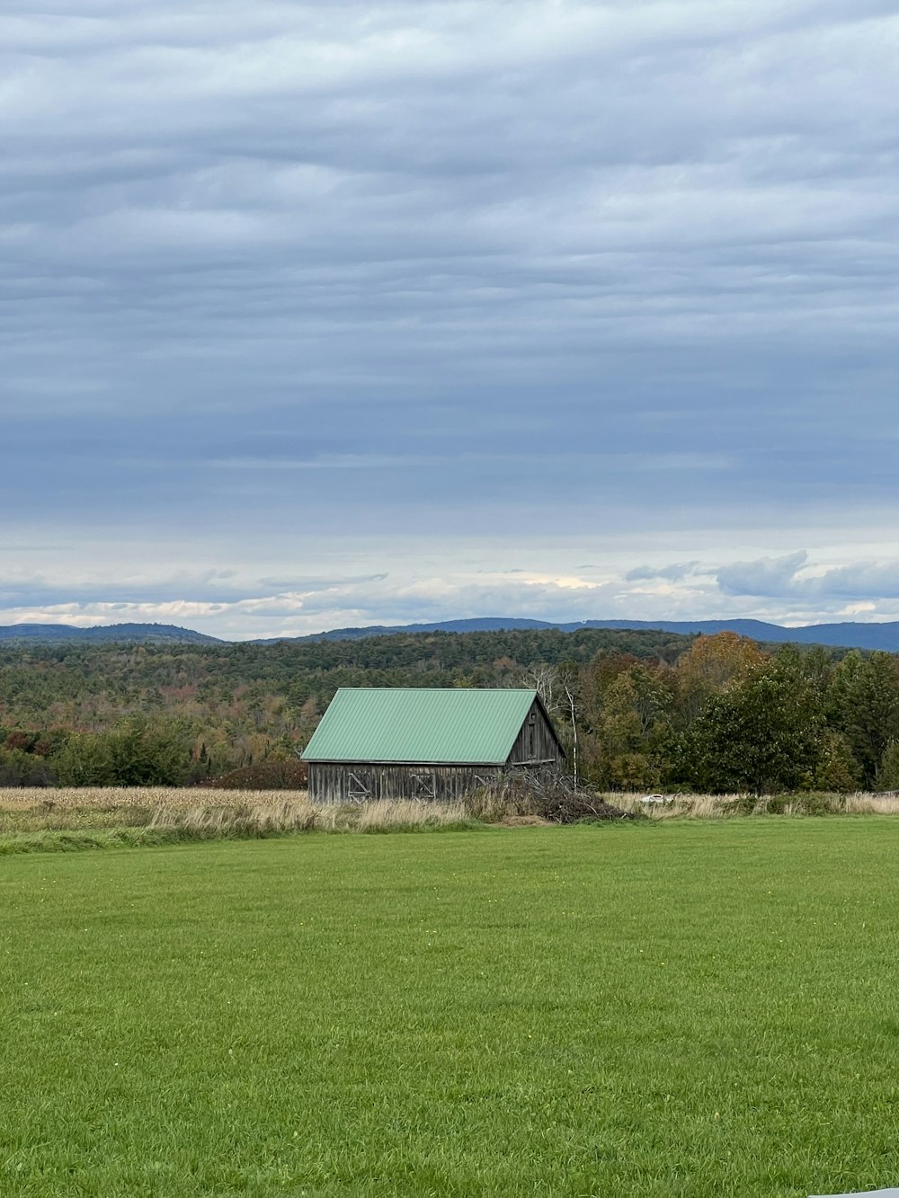 a barn in a field with mountains in the background