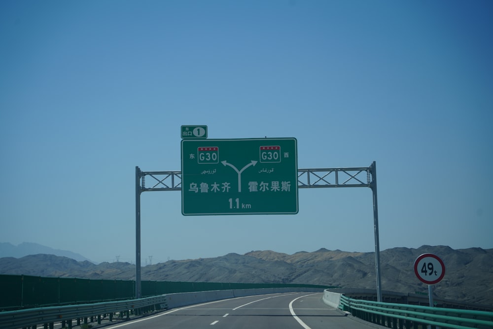 a highway sign above a highway with mountains in the background