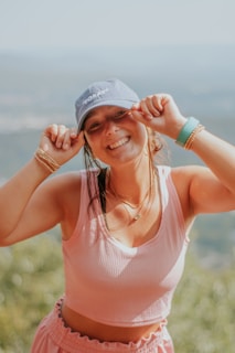 Smiling woman wearing a stylish saritfashions cap outdoors on a sunny day.