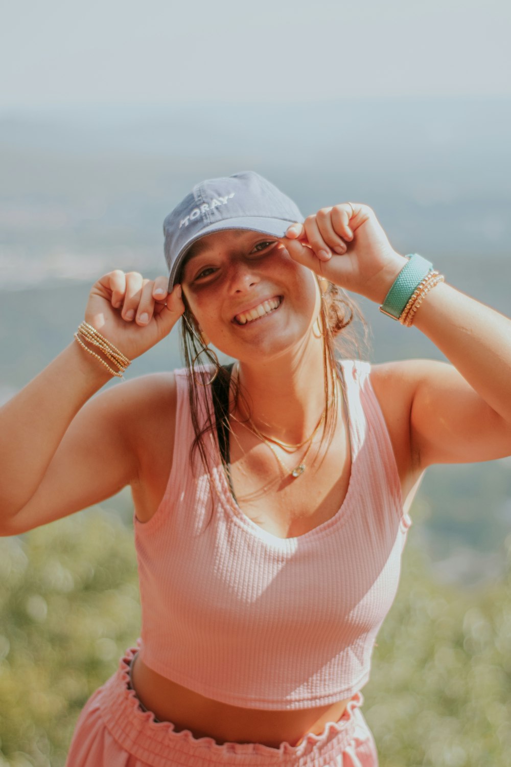 a woman in a pink tank top and a hat