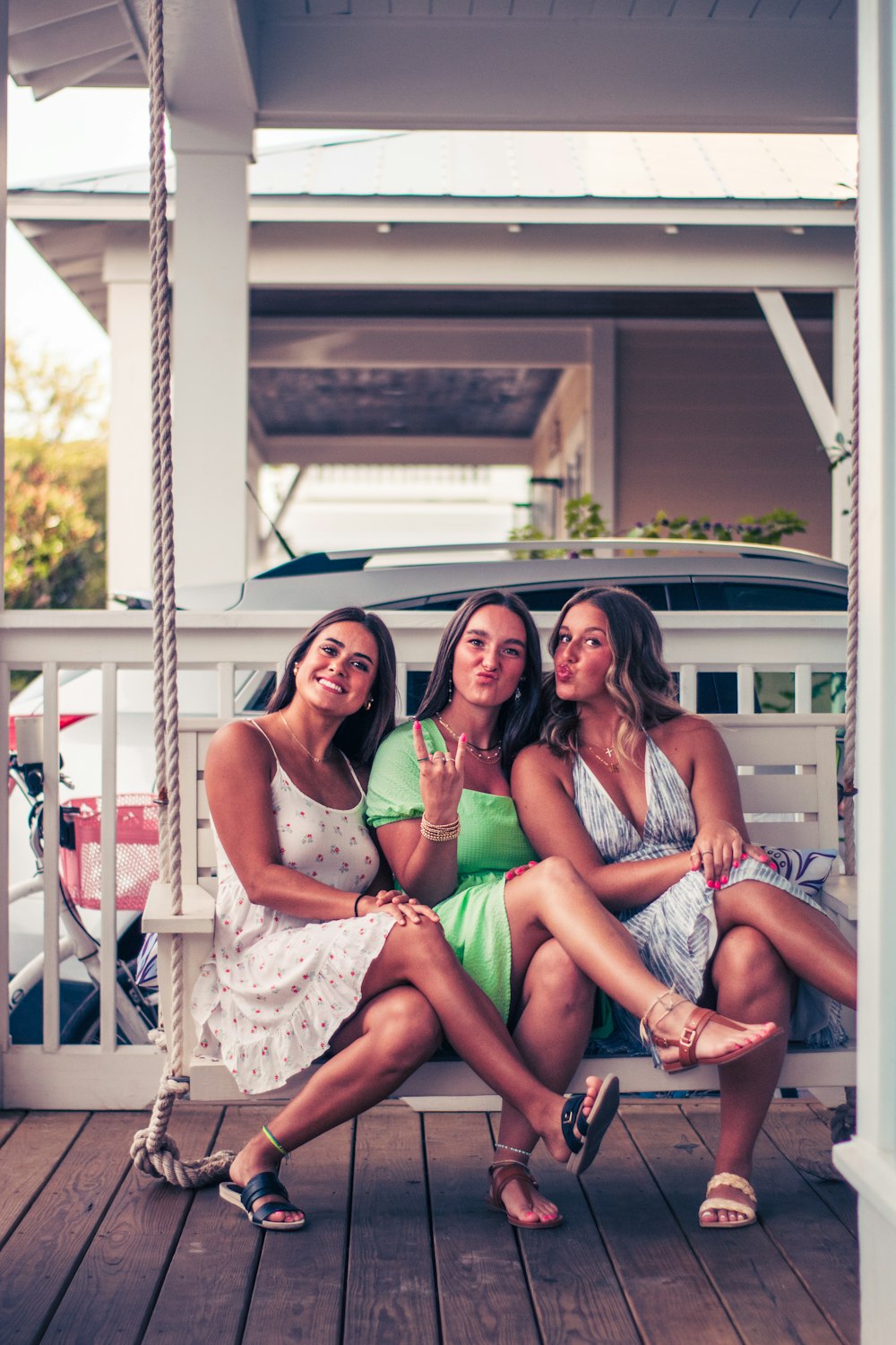 three women sitting on a porch swing posing for a picture